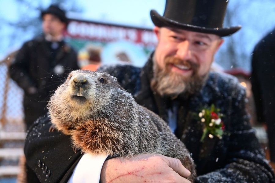 A man in a top hat holds a large rodent. "This is one time where a photograph really fails to capture the true excitement of a large squirrel predicting the weather." - Phil Connors, Groundhog Day.
