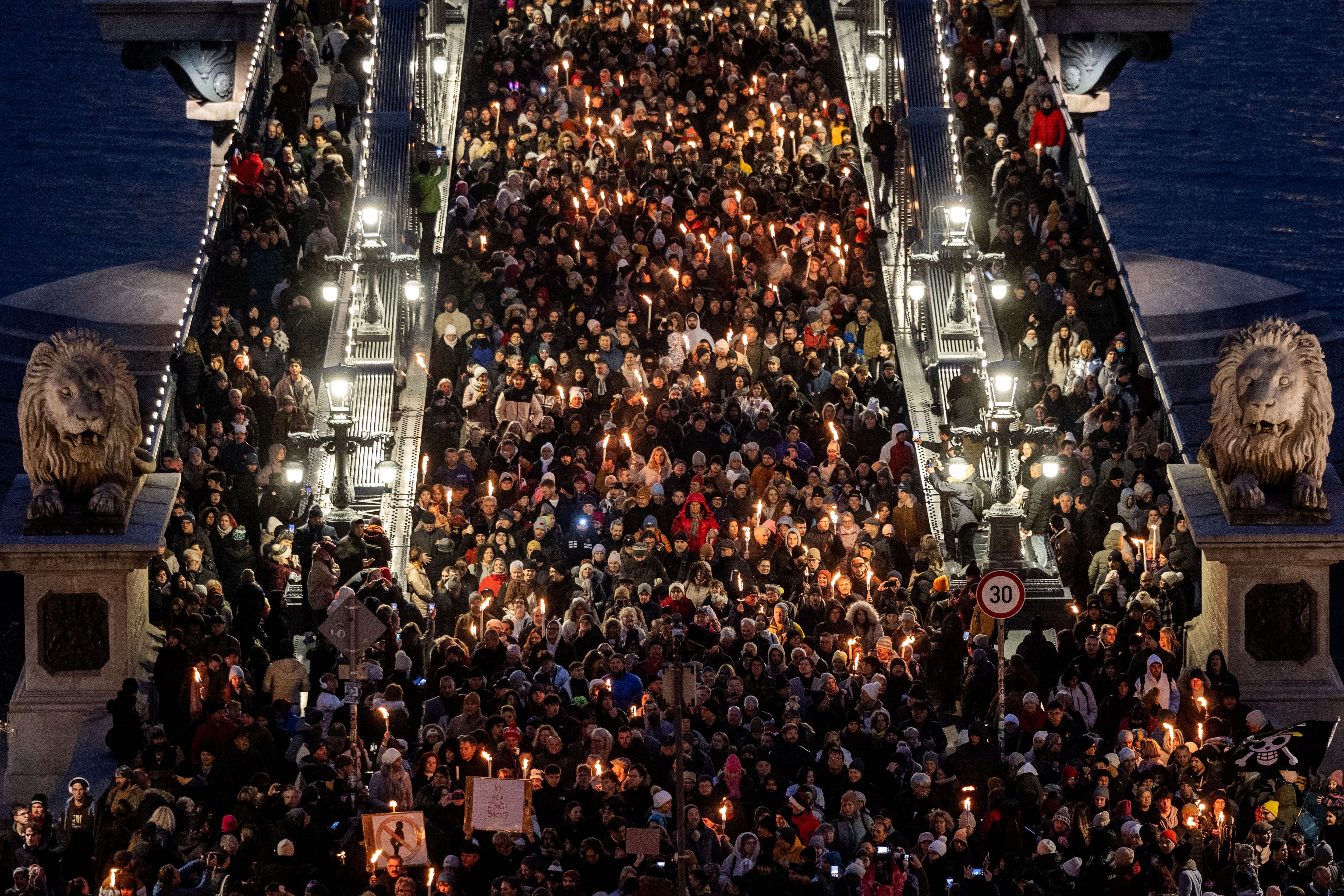 A large crowd of protesters marches across a bridge in Budapest.