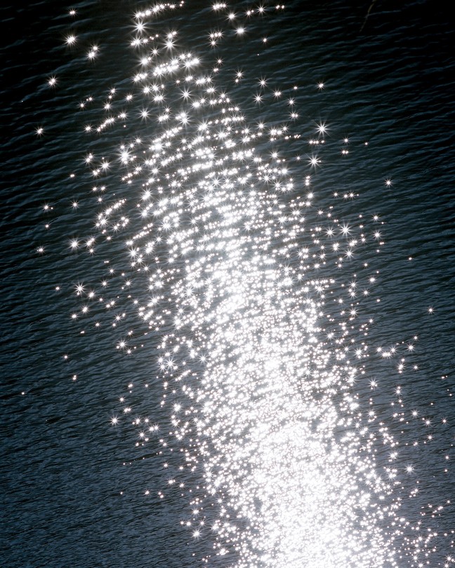 Sunlight sparkling on the ripples in a dark body of water