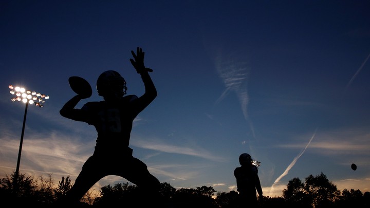 A silhouette of a high-school football player throwing a pass