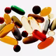 A jumble of pills and tablets in varying colors and opacities photographed on a white background
