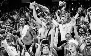 Black-and-white photo of Denmark's fans celebrate the team's victory after defeating Russia in a match
