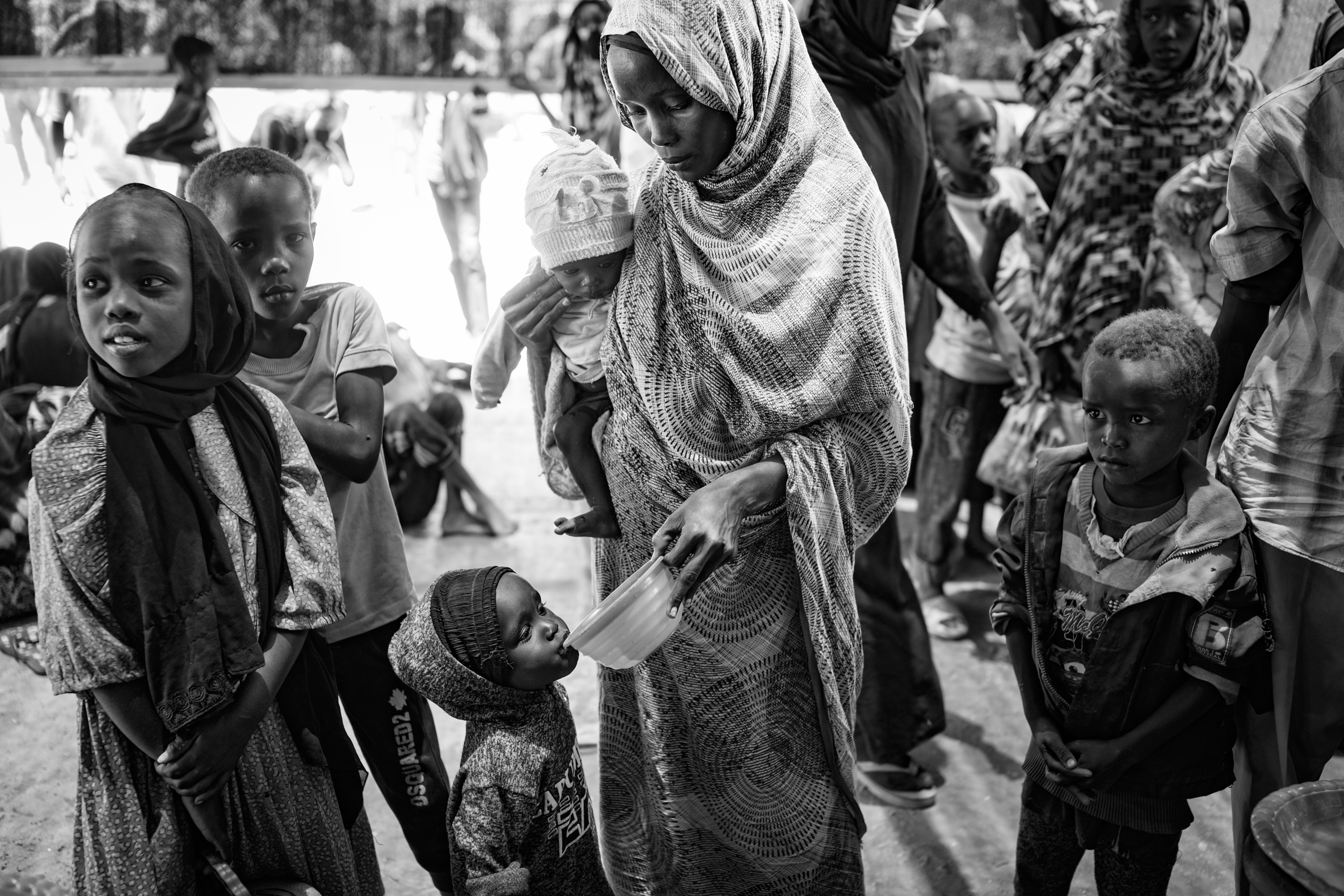 Pictures of refugees arriving at the Tiné border crossing. Islam Saboun Taher, 33, holds her six-month-old son, Waleed Abdullah Yahyiha, as she gives water to another of her four children.
