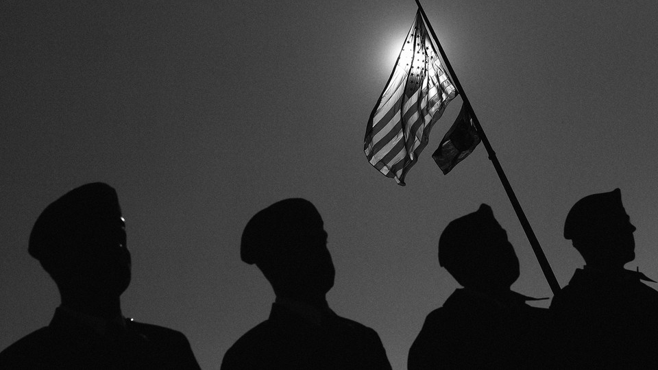 Veterans standing beneath a raised American flag