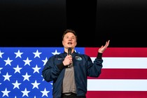 Elon Musk standing in front of an American flag