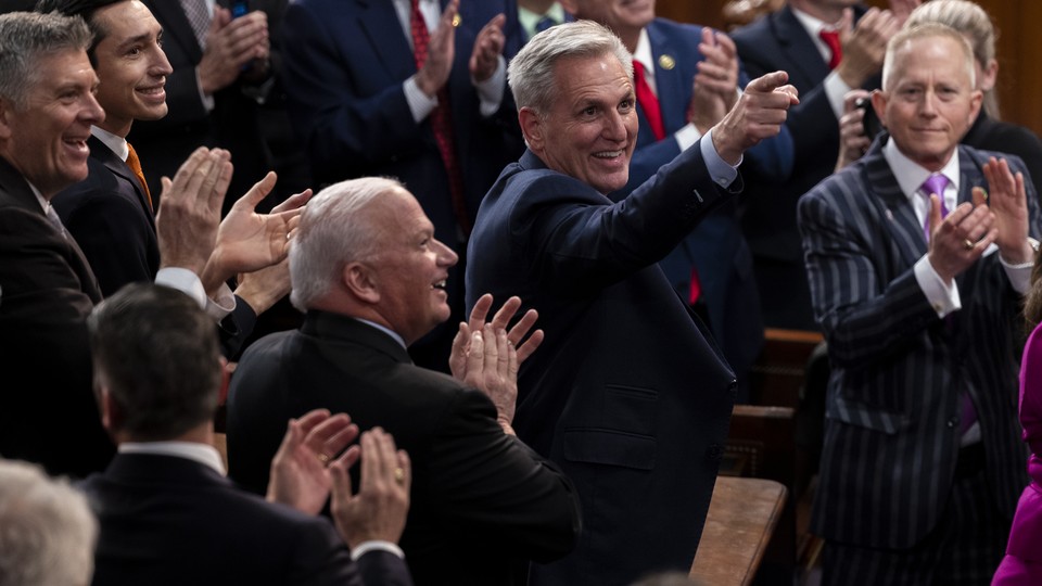 Kevin McCarthy, smiling and surrounded by clapping people, points up.