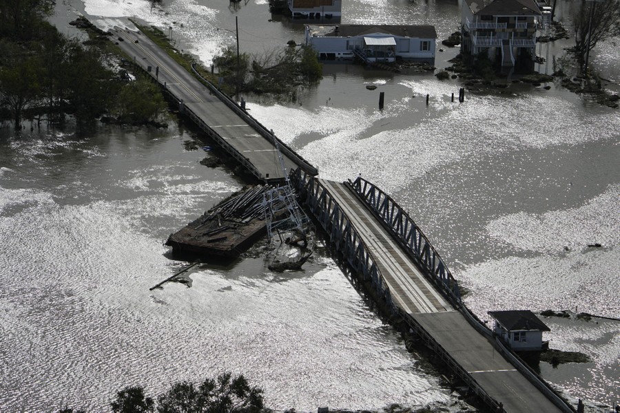 An aerial view of a barge jammed up against a damaged bridge.