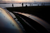 People setting up tripods reflected on a metallic surface