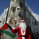 A Palestinian protester wearing Santa Claus costume stands in front of a section of the Israeli barrier during an anti-Israel protest in the city of Bethlehem on December 18, 2015. 