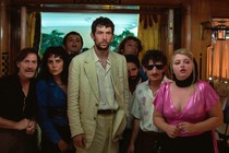 a group of people staring at something off camera, josh o'connor in the center