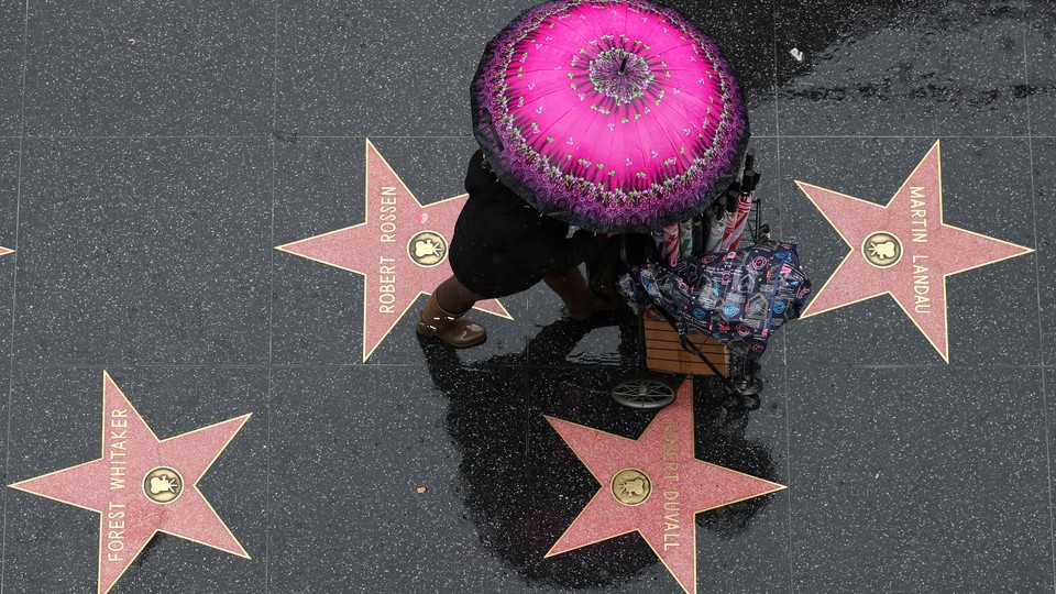 An umbrella seller walks on the Hollywood Walk of Fame in the rain in Hollywood, Los Angeles
