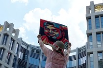 A demonstrator wearing a sun hat holds up a painting of Kilmar Abrego Garcia.