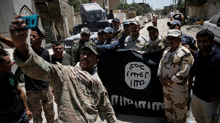 Iraqi soldiers take a selfie in front of an Islamic State flag captured during the battle to reclaim Mosul.