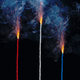 photo-illustration of red, white, blue lit fuses burning and smoking on black background