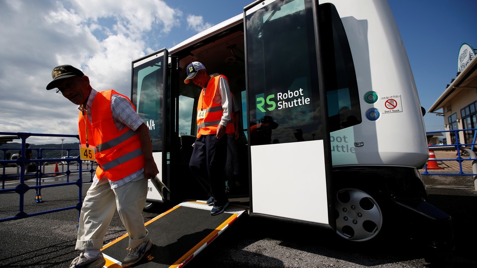 People in orange vests use a ramp to exit a driverless bus labeled "Robot Shuttle."