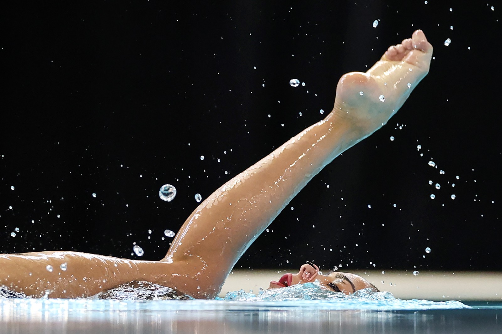 A swimmer lifts a leg out of the water during a competition.