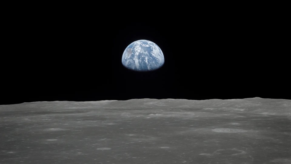 The Earth's sphere, partially occluded, hovers over the horizon of the moon.