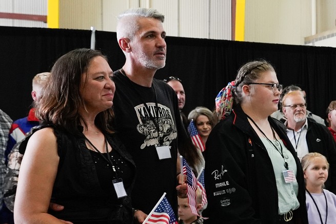 A group of people stand together. Some hold American flags