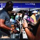 A man with a face mask stands in line at a crowded airport.