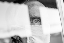 A photo of someone in a mask, looking out a window