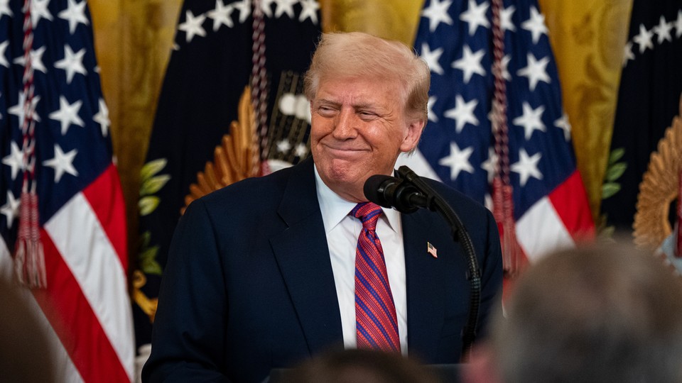 Donald Trump smiles while answering questions at a podium