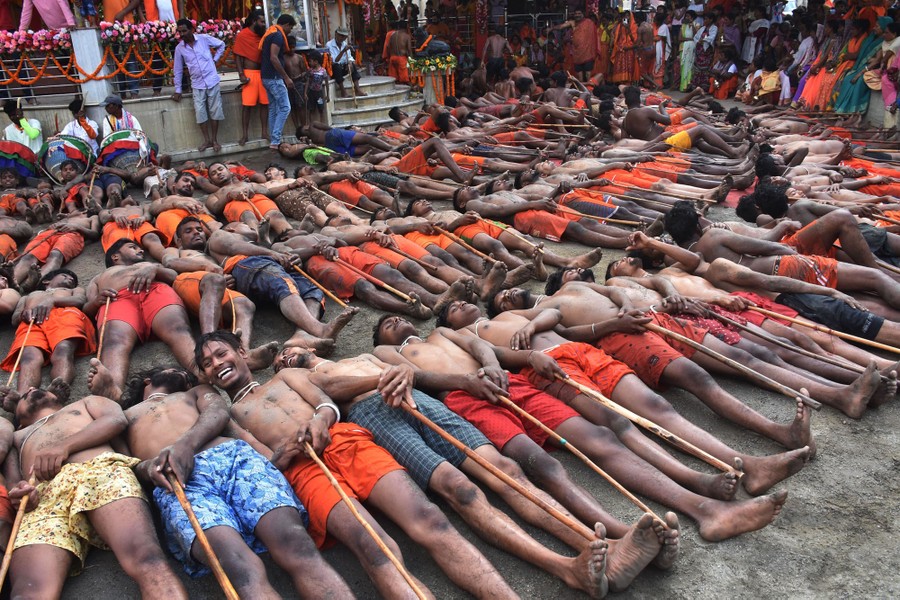Dozens of men lie on their backs in front of a temple.