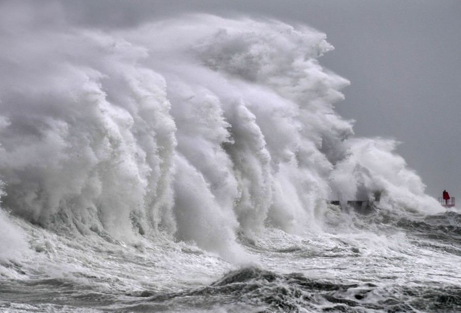 A huge wave crashes along a shoreline.