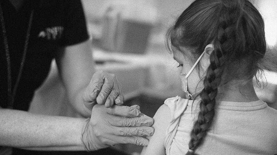a kid in a mask getting a shot