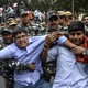 Security personnel grab student protesters during a demonstration.