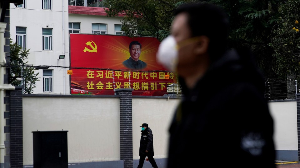 People wearing masks walk past a portrait of Chinese President Xi Jinping.