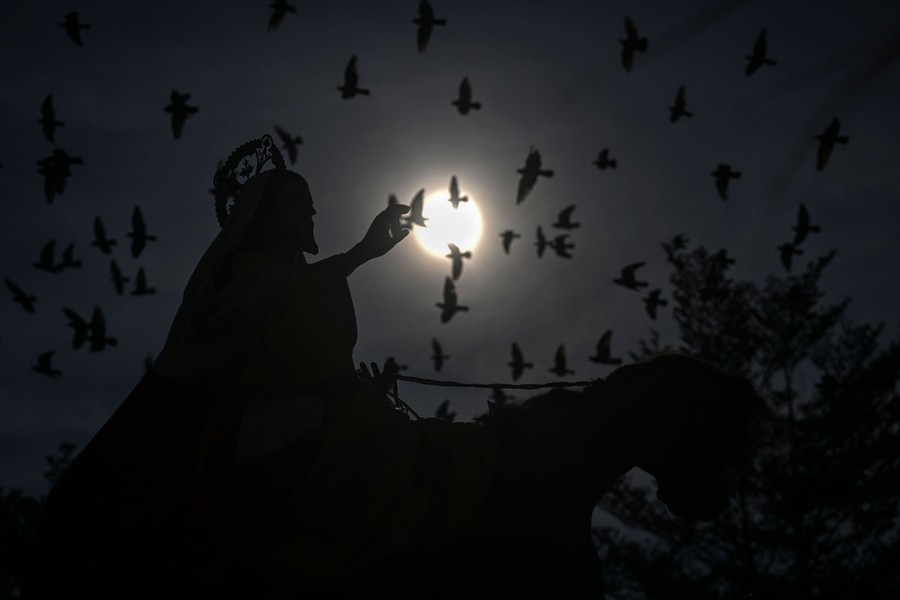 An image of Jesus Christ on horseback is silhouetted against the sky, as a flock of birds flies past.