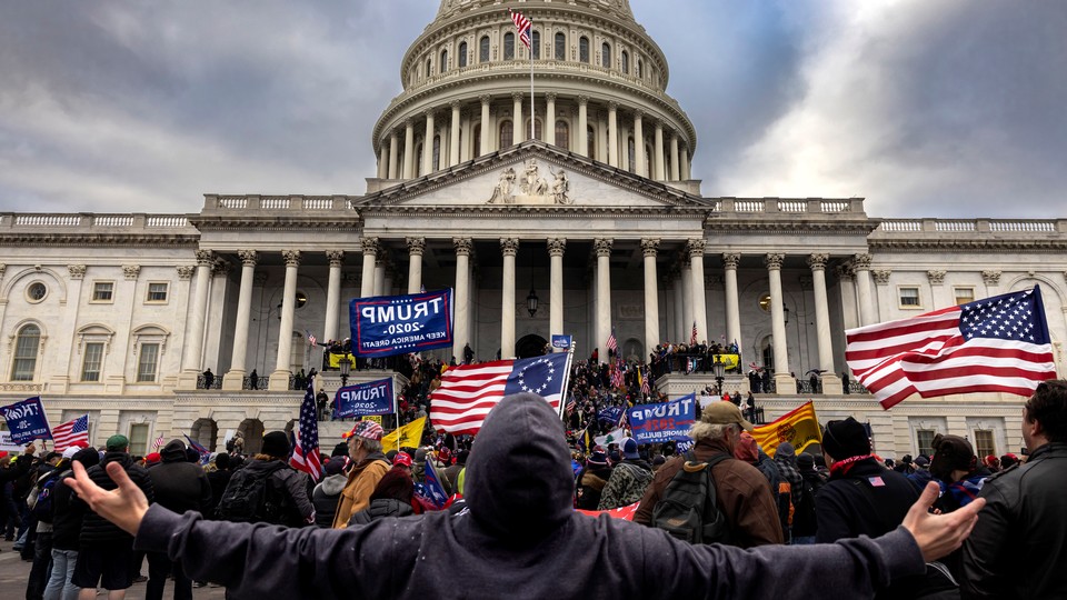 Protesters in front of the U.S. Capitol Building, holding "Trump 2020" signs and American flags