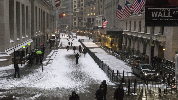 Pedestrians walk down Wall Street in the winter.