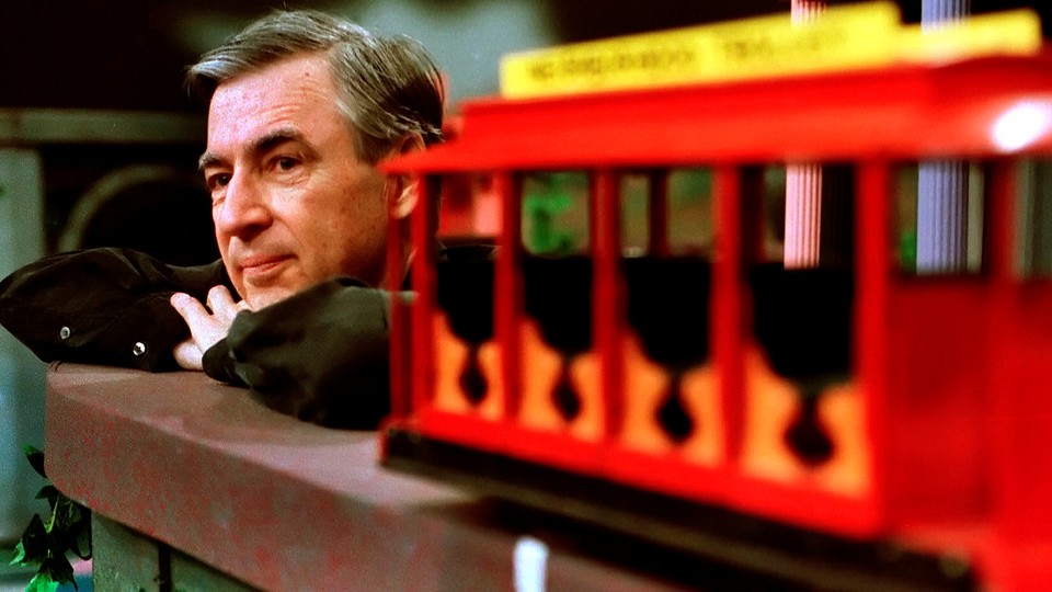 Fred Rogers resting near a trolley on a TV set