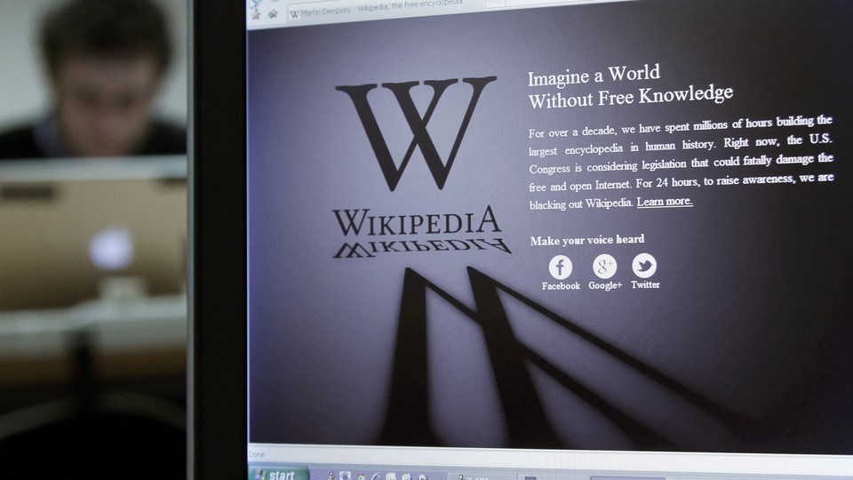 A reporter's laptop shows the Wikipedia blacked out opening page.