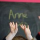 Children's hands in the air in front of a chalkboard