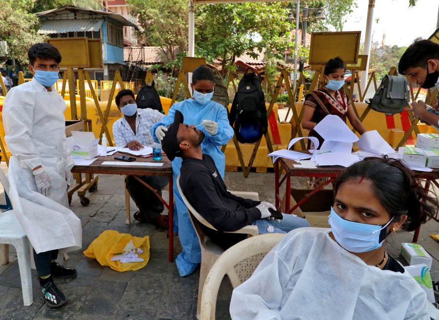 Health-care workers wait for people coming to an open-air testing station.