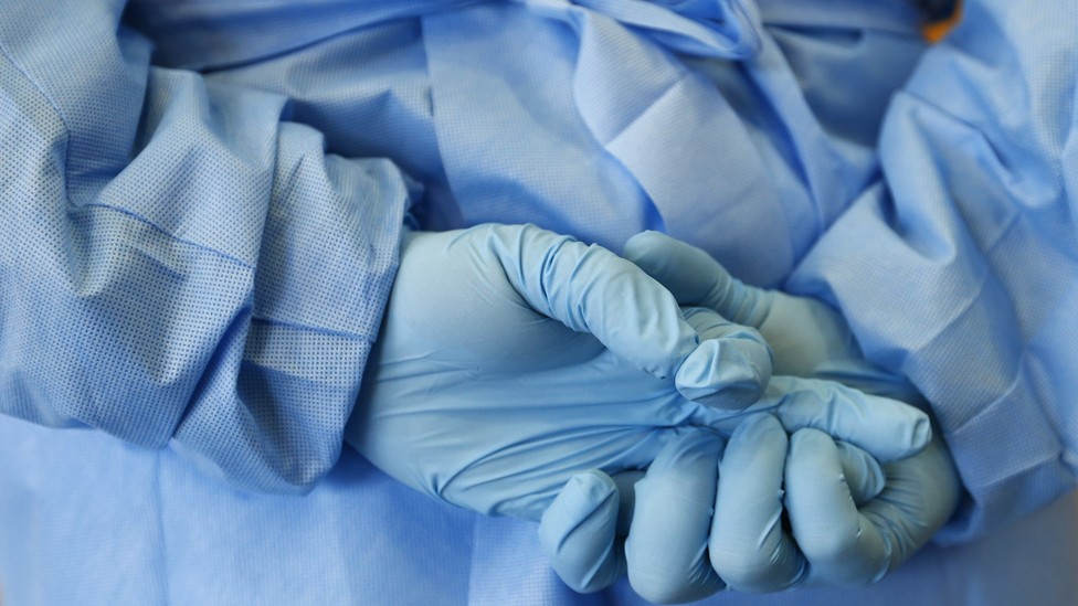 A nurse's gloved hands clasped behind back