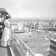 A black-and-white photograph from 1893 showing several people standing along a fence on top of a building, looking out over a large fairground filled with ornate buildings
