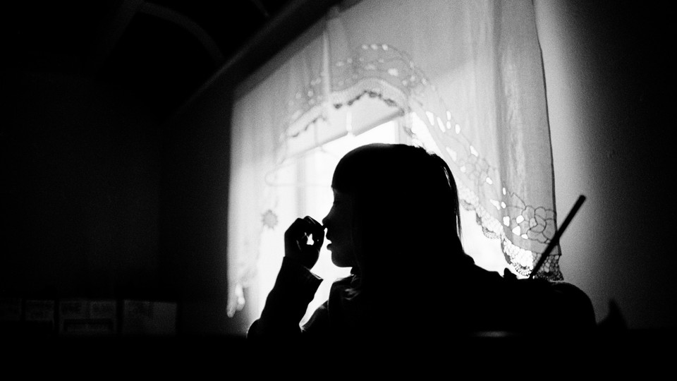 A black and white photo of a girl studying at home.