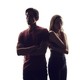 A boy and girl stand back to back. 