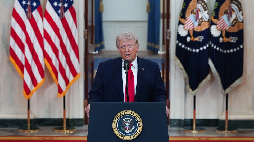 Photo du président Trump s'exprimant à un pupitre devant des drapeaux