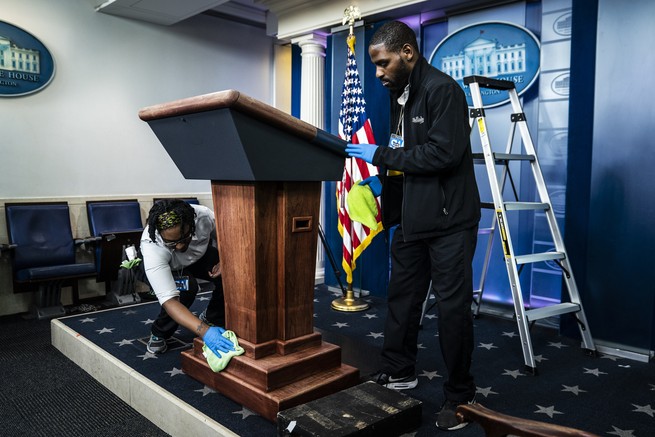 White House employees clean the podium before President Trump speaks