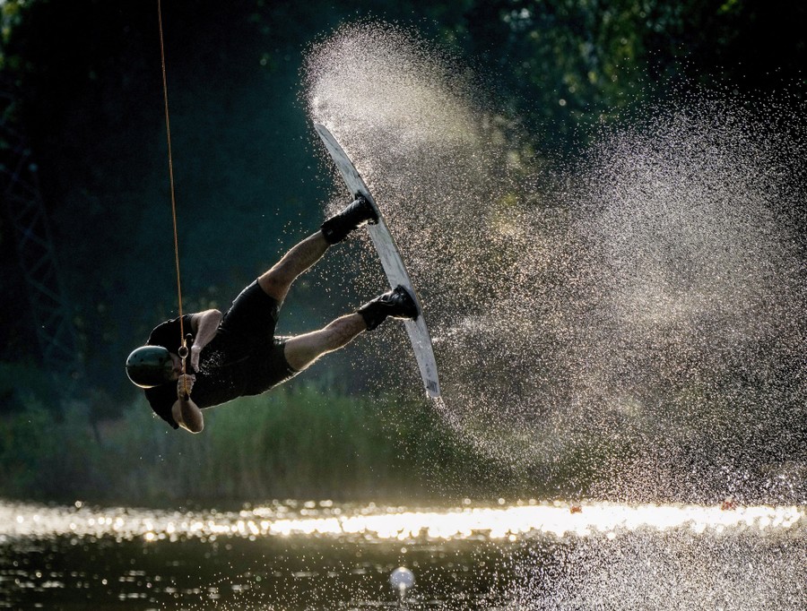 A man jumps while riding a wakeboard on a lake.
