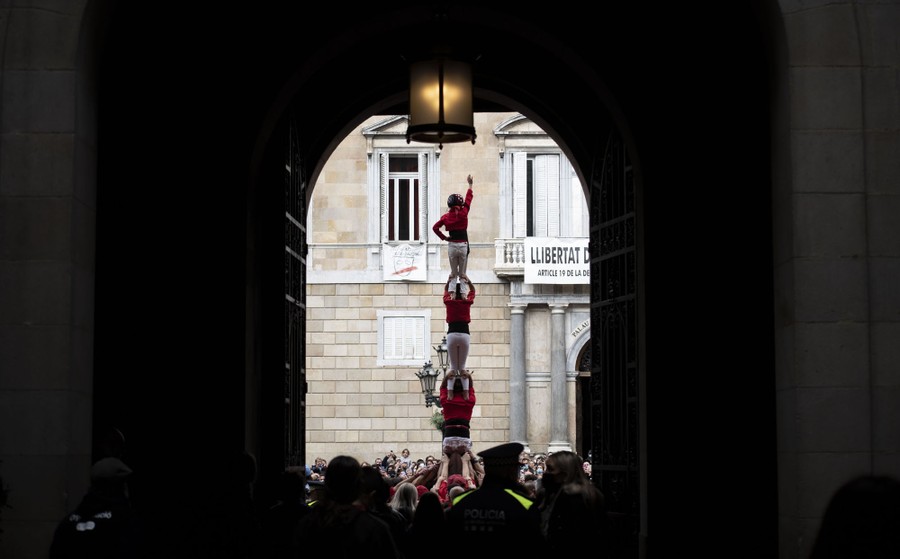 People are seen as they build a human tower, already four people high.