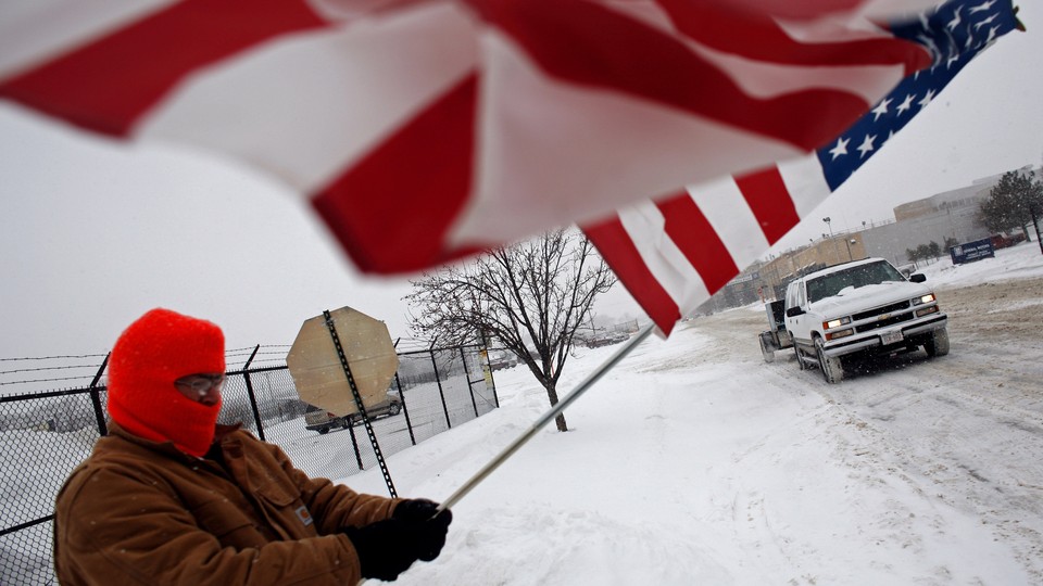 Two days before Christmas of 2008, a resident of Janesville waves a flag outside of the General Motors assembly plant in solidarity with the laid-off workers leaving the plant on its final day in operation.