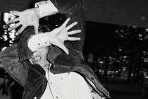 A man covers his face with his hands while he's photographed.