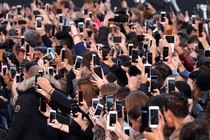 A crowd of people hold up their phones.