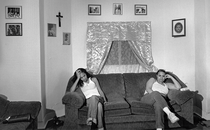 black-and-white photo of two women sitting at opposite ends of sofa in living room