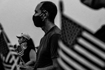 Photograph of people gathering in Washington, D.C., holding American flags, to honor those who died from COVID